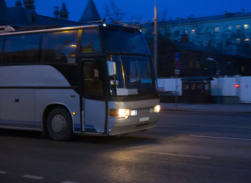 Bus moves on dark city street at night