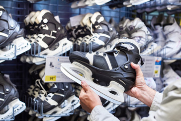 Hands of man with hockey skates in sports shop
