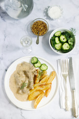 Beef Stroganoff traditional Russian dish of beef in sauce, served with fried potatoes, canned cucumbers, vodka.