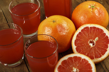 Grapefruit juice and fresh grapefruit on a wooden background. Fresh grapefruit juice in a glass bowl.