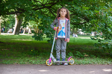 A nice girl goes for a drive on a scooter in a park
