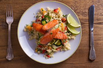 Salmon with tomato couscous, zucchini and lime. View from above, top studio shot