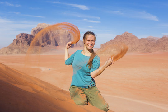 young woman with a smile sprinkled sand in the desert