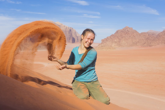 young woman with a smile sprinkled sand in the desert