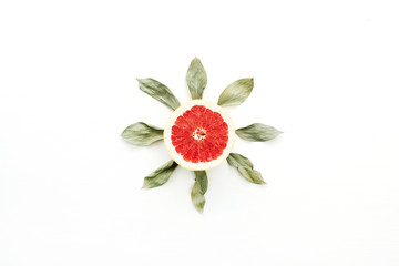 Sun symbol made of sliced grapefruit and leaves. Flat lay, top view summer concept.