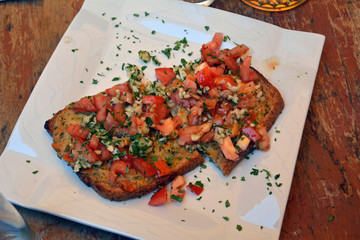 Authentic traditional spanish tapas on a plate. Bruschetta on crusty bread with cheese,tomato,onion and parsley.Food, appetizer. Antipasto in bar.