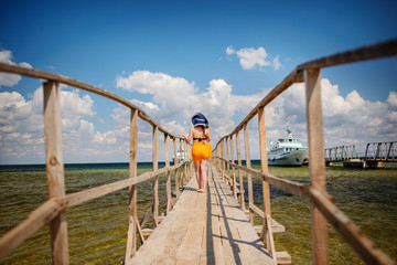 Fototapeta na wymiar girl in a blue hat goes along the pier
