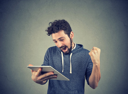 Happy man with tablet holding fist up