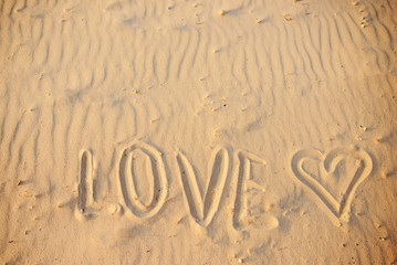 big text LOVE in the sand of the beach