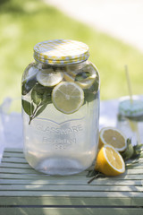 Lemonade in the jug and lemons with mint on the table outdoor