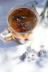 Herbal lavender tea in glass cup with lavender flowers