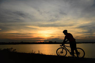 Fototapeta na wymiar Silhouette of handsome man lift up bicycle on your head on sunset,sport man concept