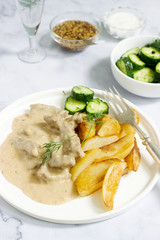 Beef Stroganoff traditional Russian dish of beef in sauce, served with fried potatoes, canned cucumbers, vodka.