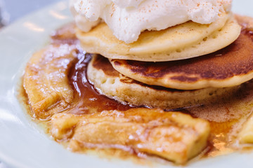 Close up Pancakes with caramel-banana syrup topping with whip cream and mint leaves.