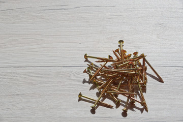 Yellow shiny screws scattered on wooden background