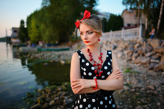 A beautiful young woman dressed standing by the lake