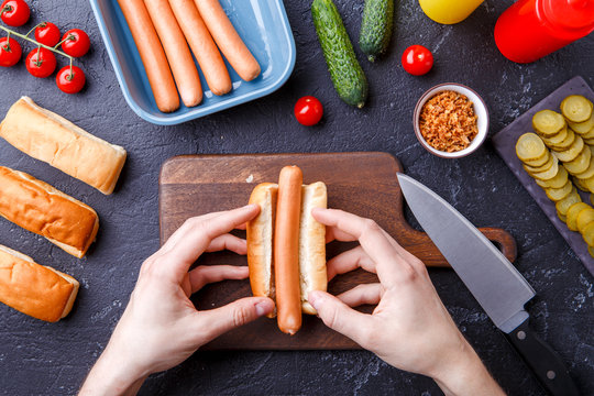 Image from above of man doing hotdogs on table