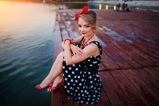 A beautiful young woman dressed sitting on the pier