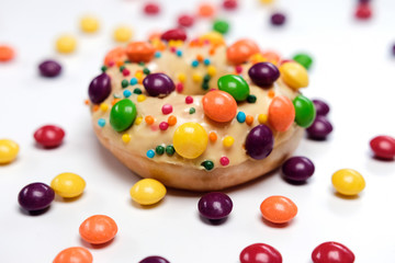 Appetizing golden donut sprinkled with colorful chocolate pellets.