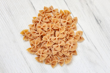 Spilled uncooked farfalle on a white wooden table