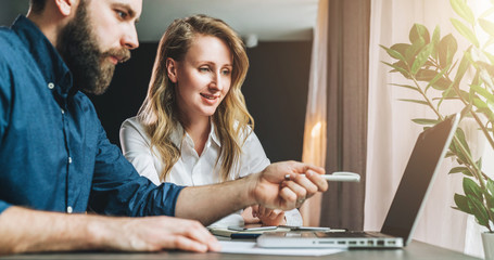 Business meeting. Teamwork. Businesswoman and businessman sitting at table in front of laptop and...