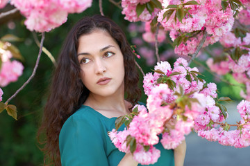 Obraz premium beautiful girl posing near sakura flowers