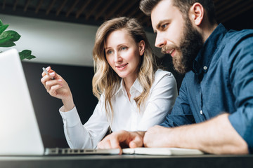 Business meeting. Teamwork. Businesswoman and businessman sitting at table in front of laptop and...