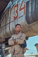 Fototapeta na wymiar Mechanic in uniform standing near a war fighter-interceptor in an open-air museum.