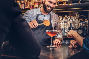 Cheerful stylish brutal barman serves an attractive couple who spend an evening on a date.