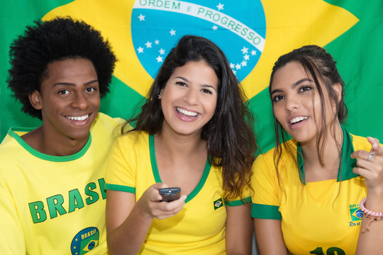 Three brazilian fans watching match of Brazil live at tv