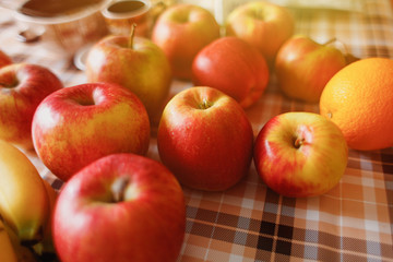 Fruit on the table in the kitchen. Apples, oranges, bananas. Fresh harvest. Sunlight, close view
