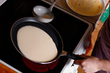 A woman making pancakes in the kitchen.