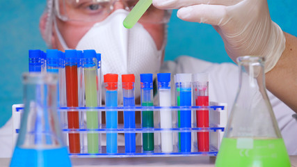 The alchemist checks the test tubes with a test of different compositions, in a white coat, a...