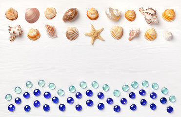 Exotic sea shells and glass beadson a white wooden background. Concept of summer travel and beach...