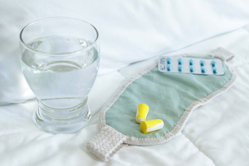 Blister pack of sleeping pills, blindfold and glass of water