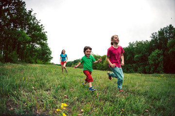 Fototapeta premium A woman with children runs along the grass.