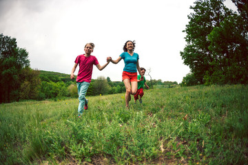 Fototapeta premium A woman with children runs along the grass.