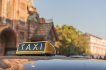 The big taxi sign on the background of city