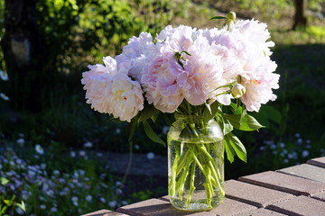 A bouquet of white and pink peonies in a glass vase