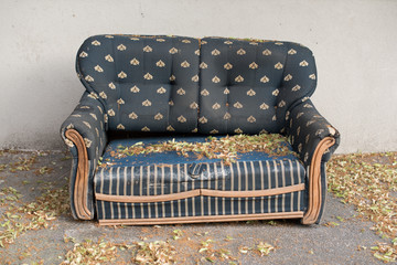Old ruined and abandoned retro style blue armchair in the street.
