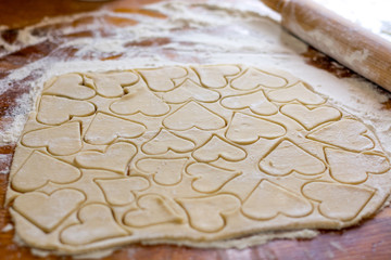 Preparation of the dough, roll out with a rolling pin and cut shapes in the form of hearts. Baking cookies for the holiday. Close-up.