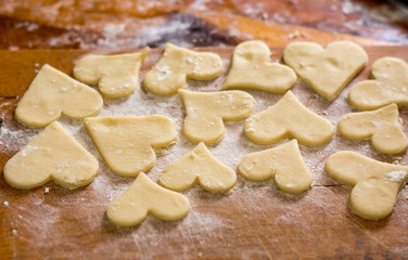 Fototapeta na wymiar Preparation of the dough, roll out with a rolling pin and cut shapes in the form of hearts. Baking cookies for the holiday. Close-up.