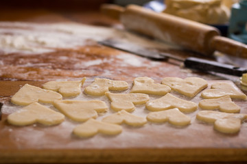 Preparation of the dough, roll out with a rolling pin and cut shapes in the form of hearts. Baking cookies for the holiday. Close-up.