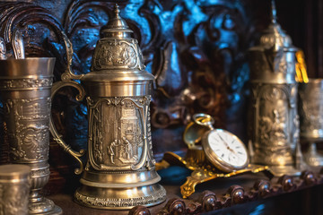Fototapeta na wymiar Old antique vintage dishes, large silver mugs, watches, selective focus