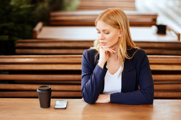 Beautiful woman drinking coffee in a cafe and phone