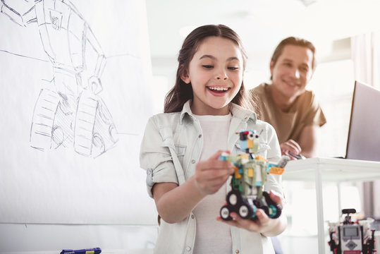 Portrait of happy female child looking at modern toy. Outgoing man using gadget during lesson. Toys of future concept