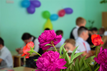 School, the last bell. Exam. Abstract image of pupils in the background of bouquets of flowers. Selective focus.