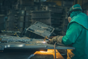 Man in protective clothing cutting steel with blow torch