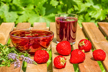 Strawberries, jam and juice on the table in the garden