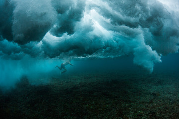 Underwater view of the surfer trying to pass powerful ocean wave
